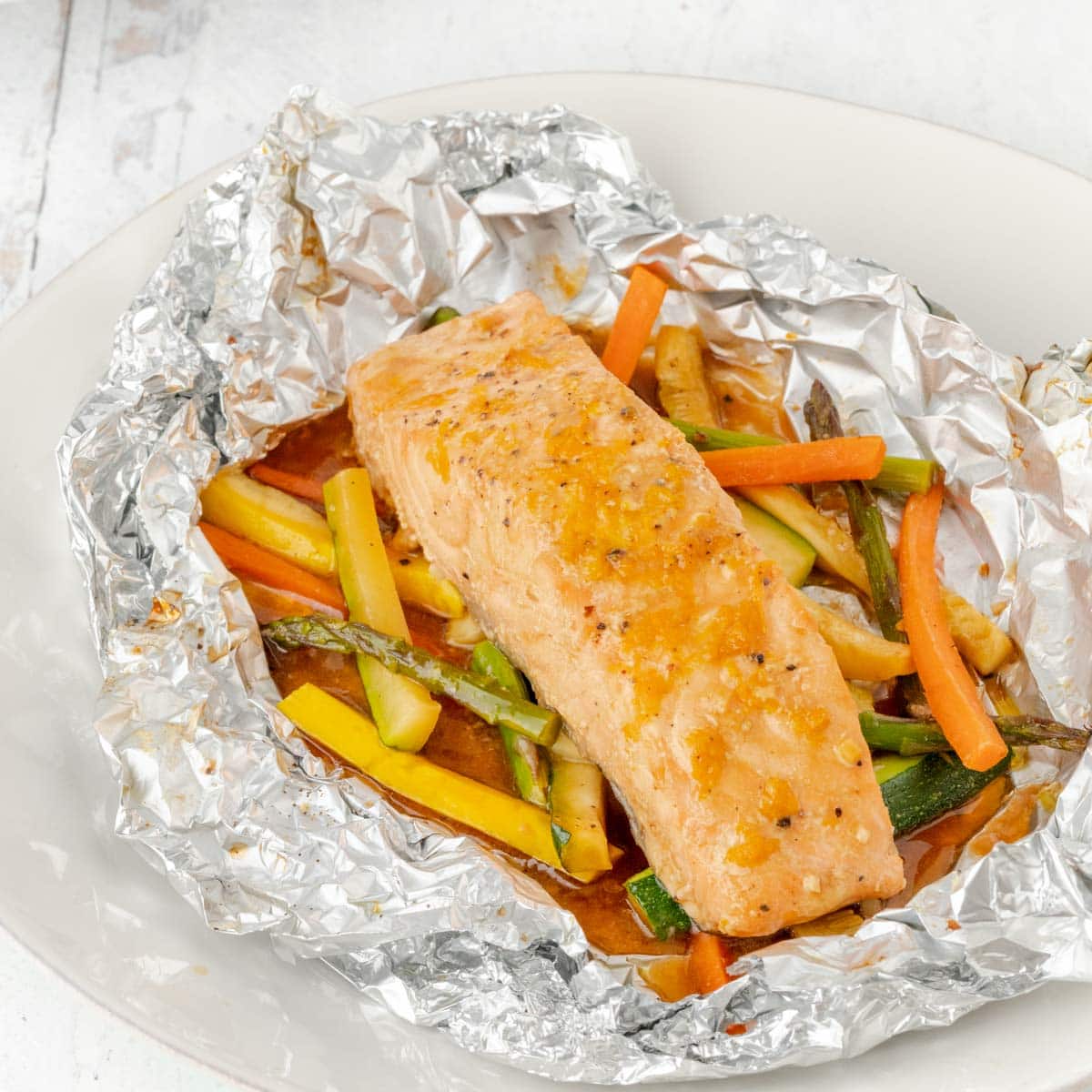 Salmon and vegetables baked in foil, with foil cut open to show inside