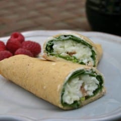blue plate holding 1 stuffed crepe, cut in half to show the ham, scrambled egg, and spinach inside.