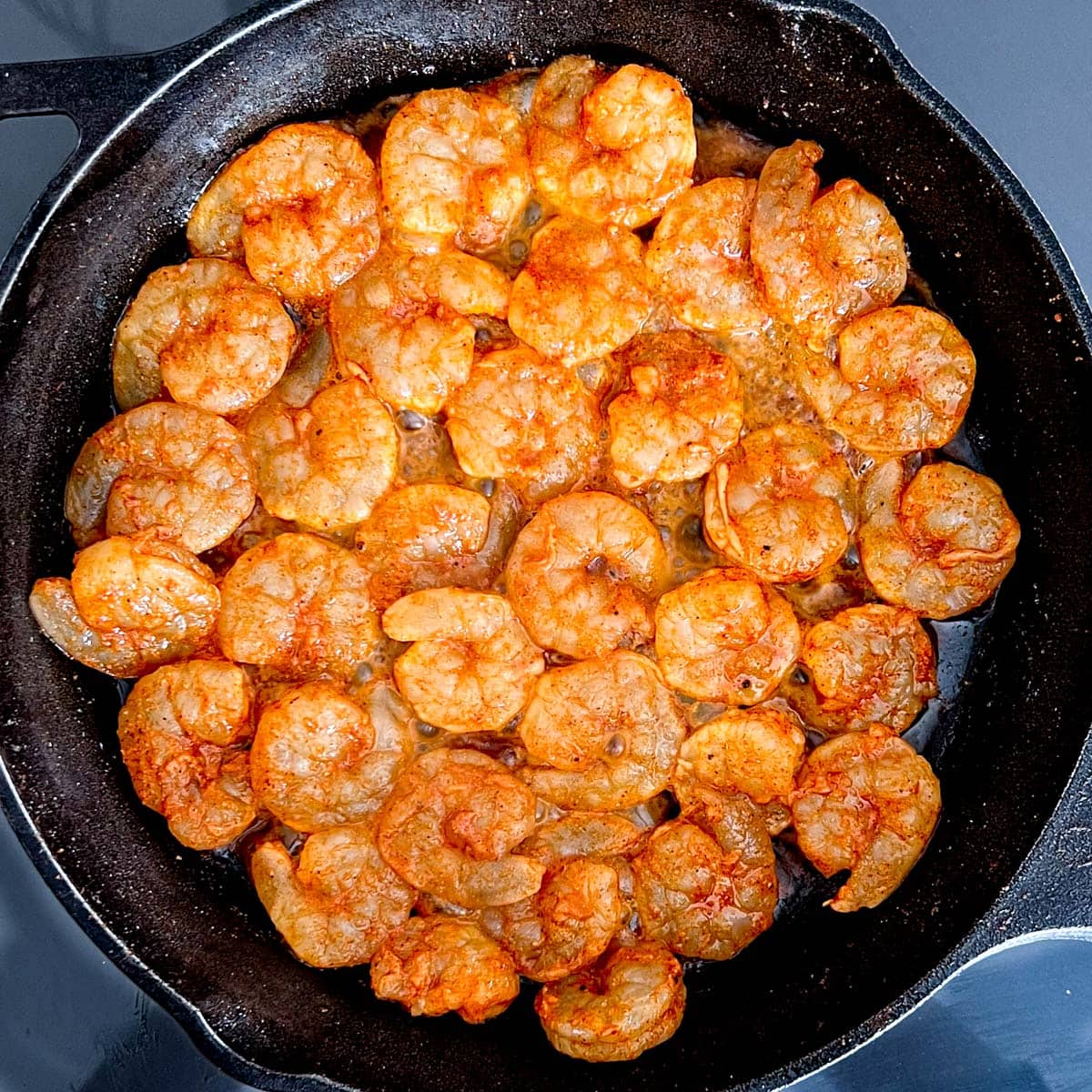 Overhead shot of shrimp cooking in a cast iron skillet