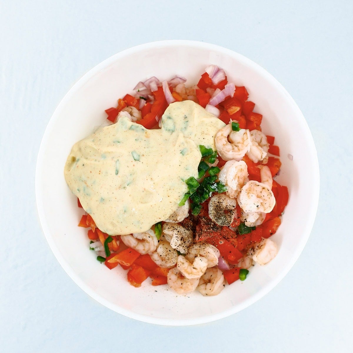 Assembling the ingredients for spicy shrimp salad in a bowl.