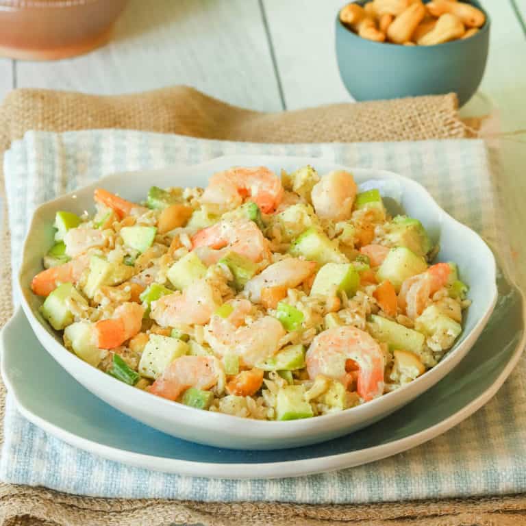 Close up shot of Shrimp Salad with Rice and Avocado on a blue plate, sitting top of a blue and white napkin