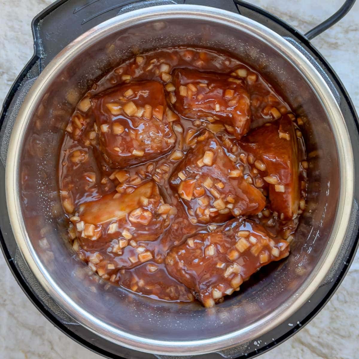 Seared beef short ribs in slow cooker with sauce completely covering them.