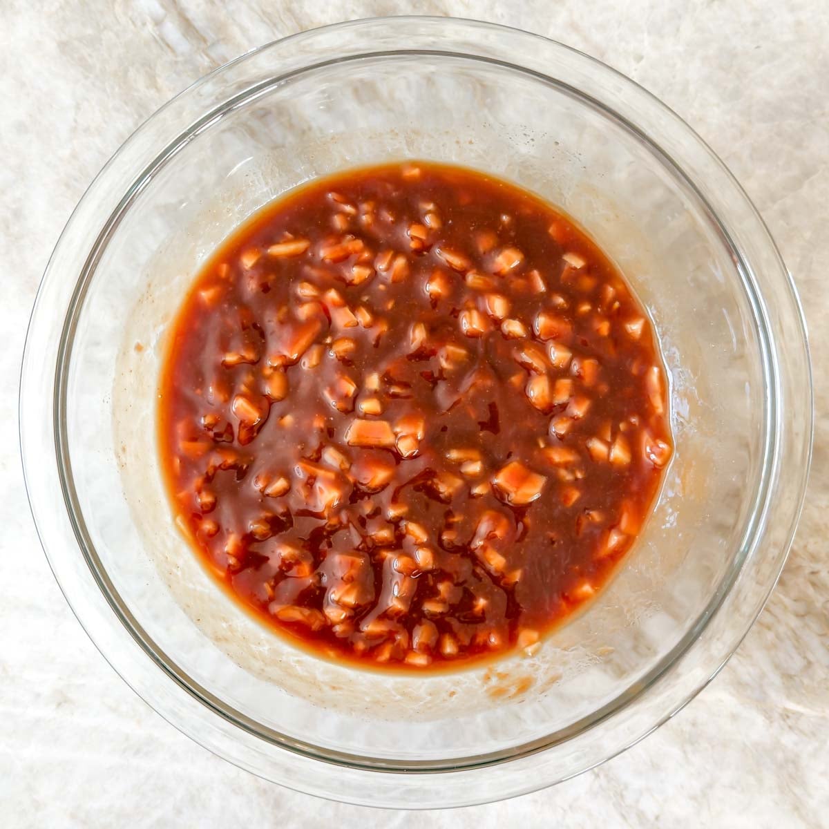 Glass mixing bowl holding tangy, savory sauce for beef short ribs.