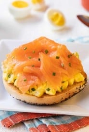 Square white plate with Toasted Bagel with Egg Salad and Smoked Salmon