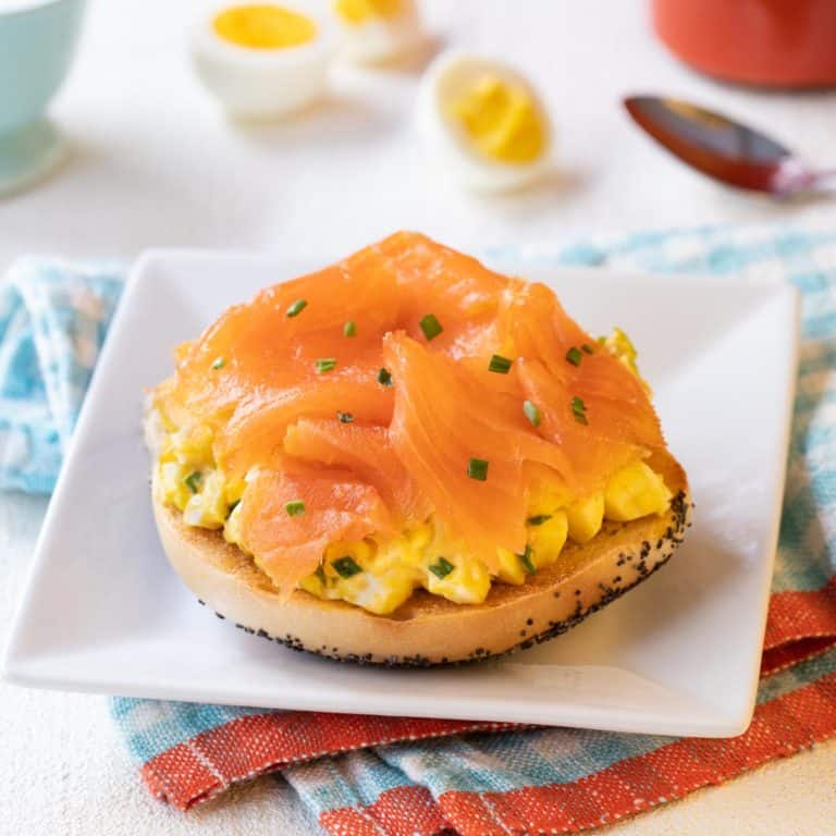 Square white plate with Toasted Bagel with Egg Salad and Smoked Salmon