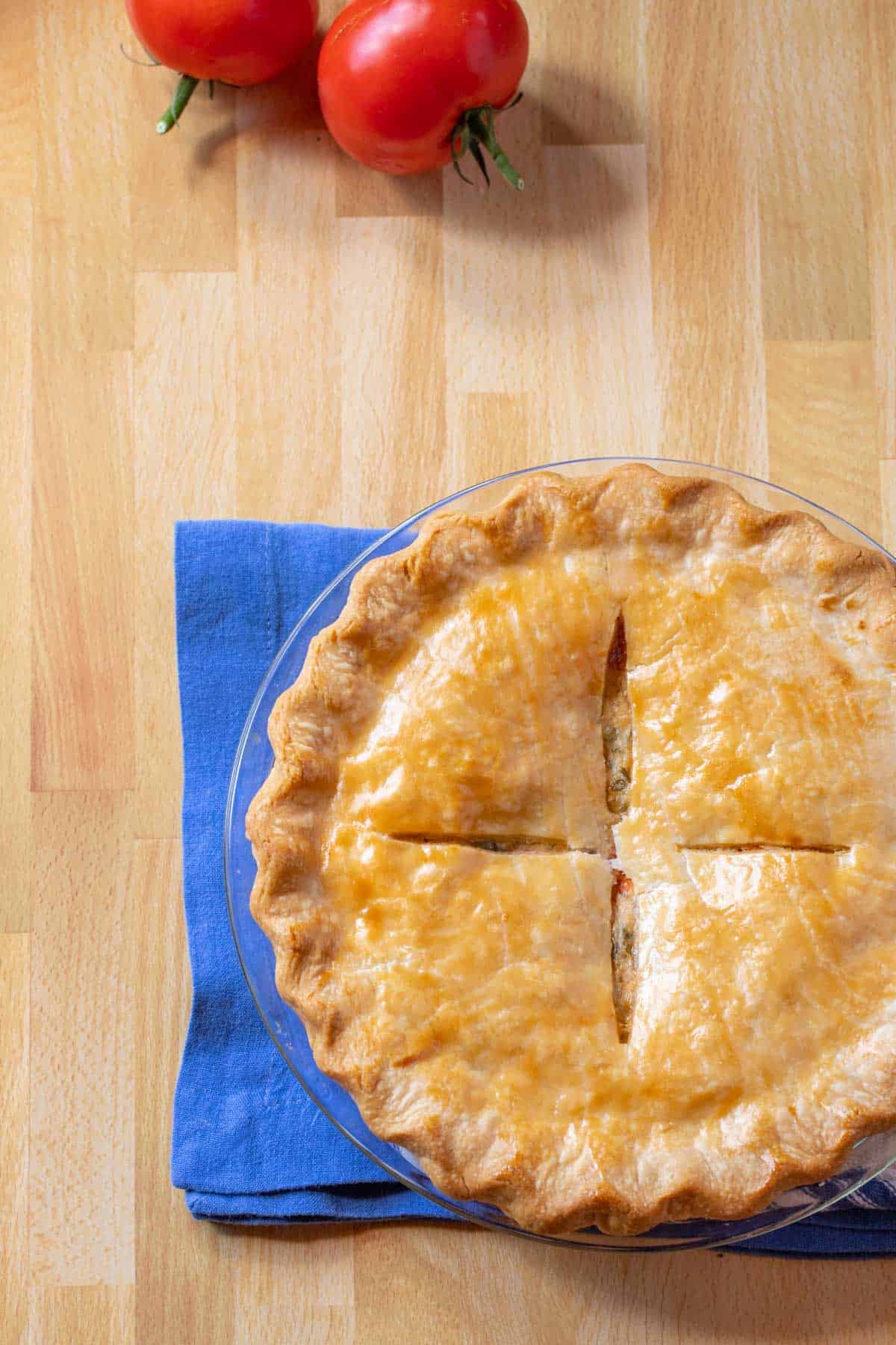 photo of whole Southern Tomato Pie with 2 fresh tomatoes on top of photo