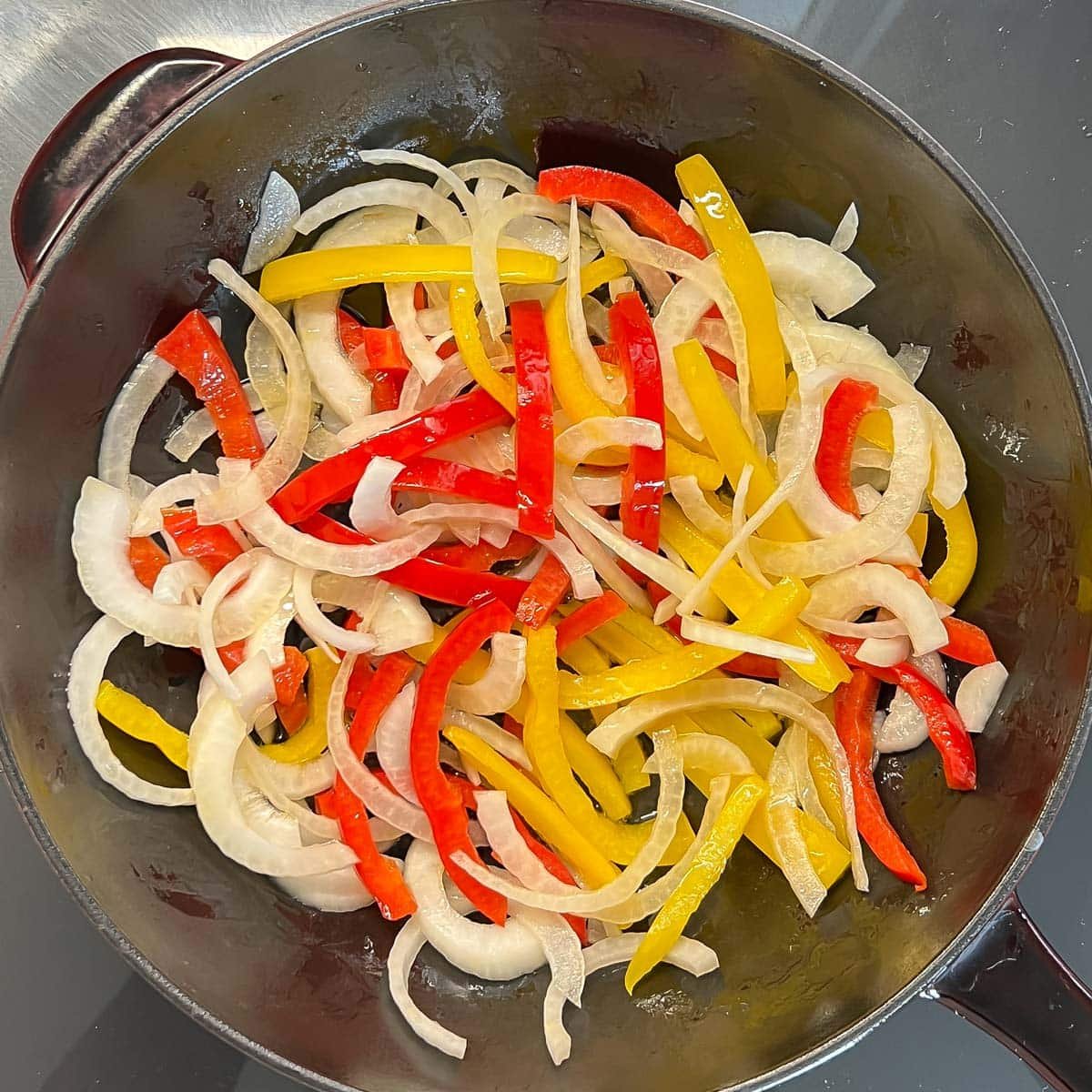 Strips of yellow and red bell peppers and onion in a large pan to make Mexican Grilled Chicken.