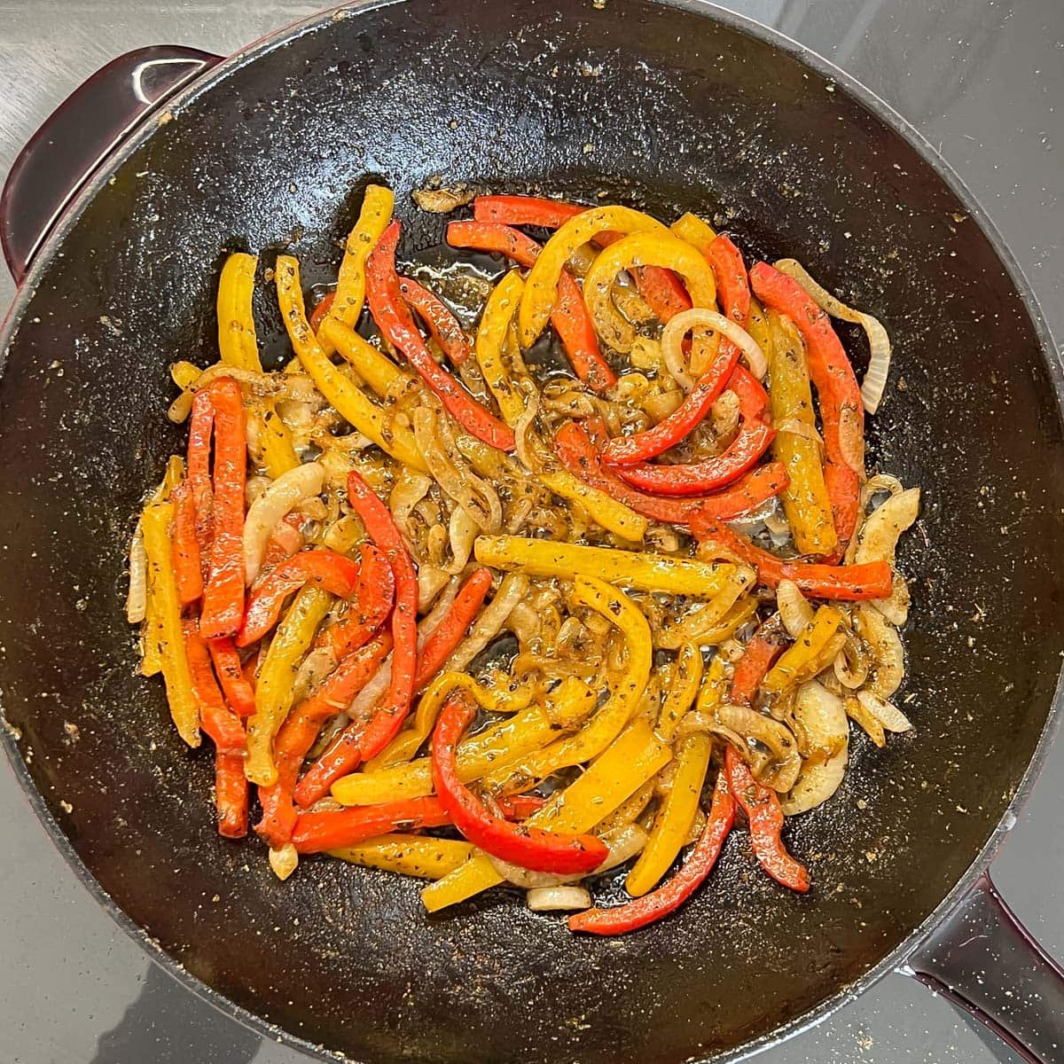 Softened and seasoned bell peppers and onion in a large pan for Mexican Grilled Chicken.