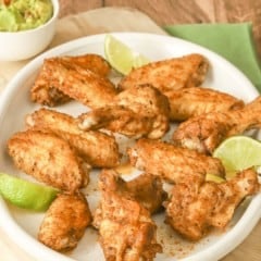 round white platter filled with spicy chicken wings; guacamole in a bowl on the side