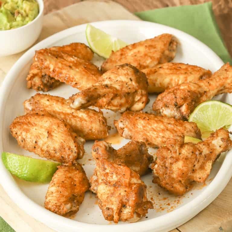 round white platter filled with spicy chicken wings; guacamole in a bowl on the side