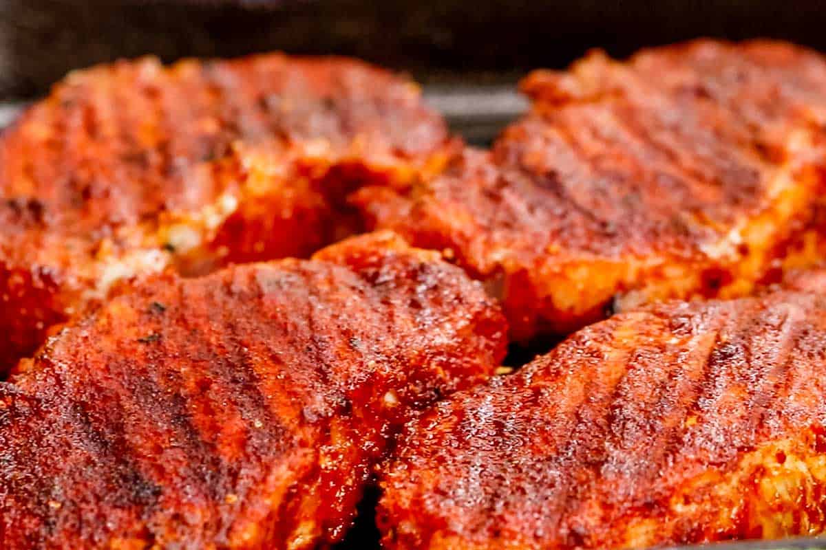 close up of 4 spicy pork chops on a grill. pan