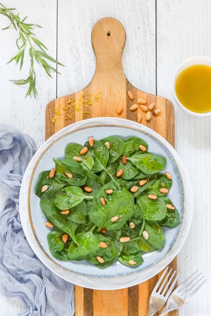 Overhead shot of a plate holding a serving of Easy Spinach Salad with Lemon Dressing on the side