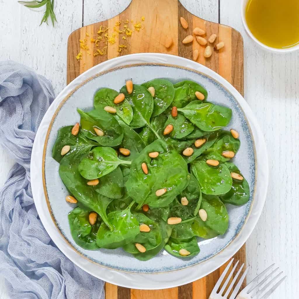 Overhead shot of a plate holding a serving of Easy Spinach Salad with Lemon Dressing on the side