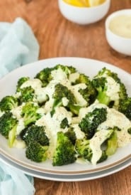 white plate holding steamed broccoli with lemon and curry mayo sauce