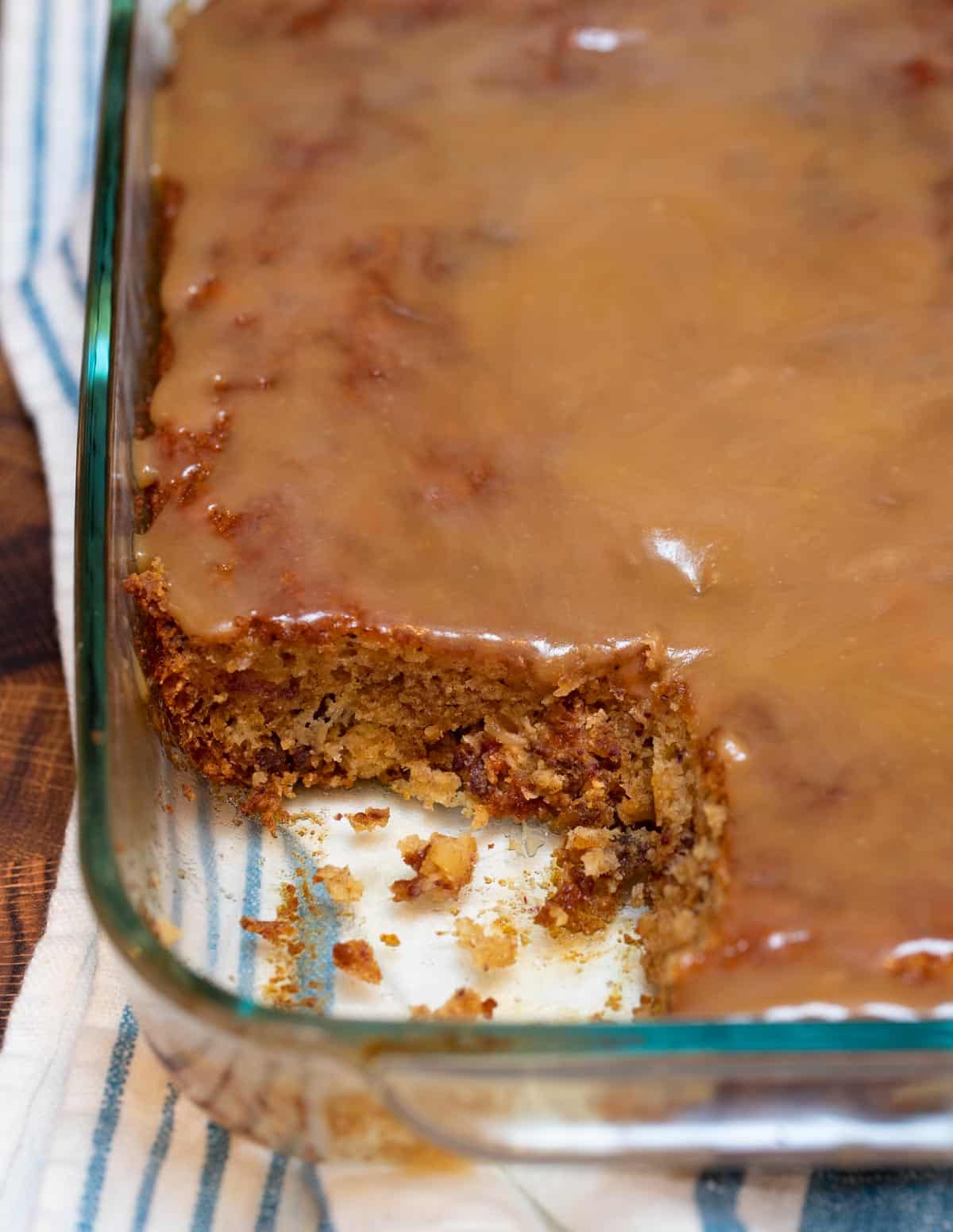 Glass baking dish with a piece cut out of Sticky Toffee Pudding