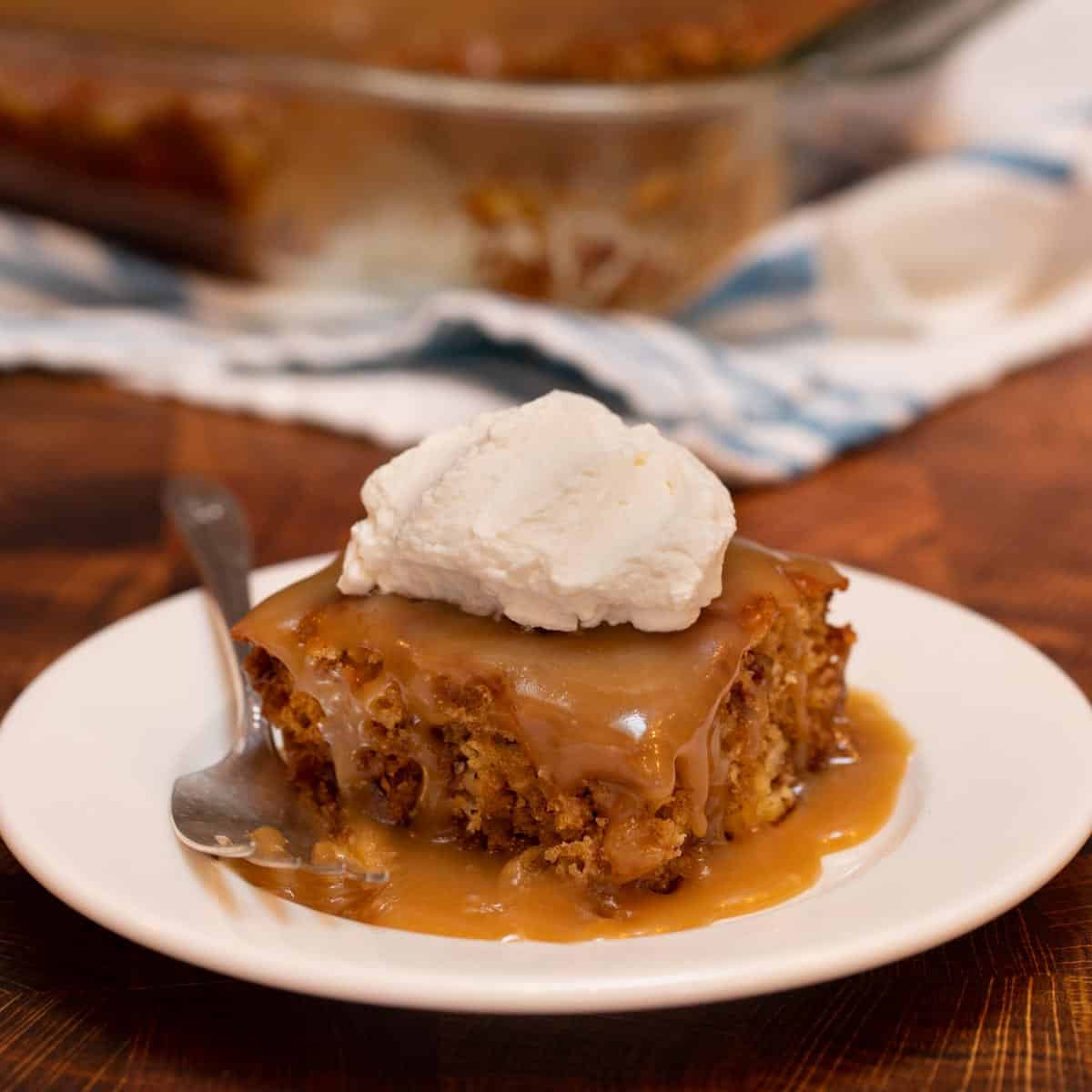 White plate with a slice of Sticky Toffee Pudding with Rum Whipped Cream