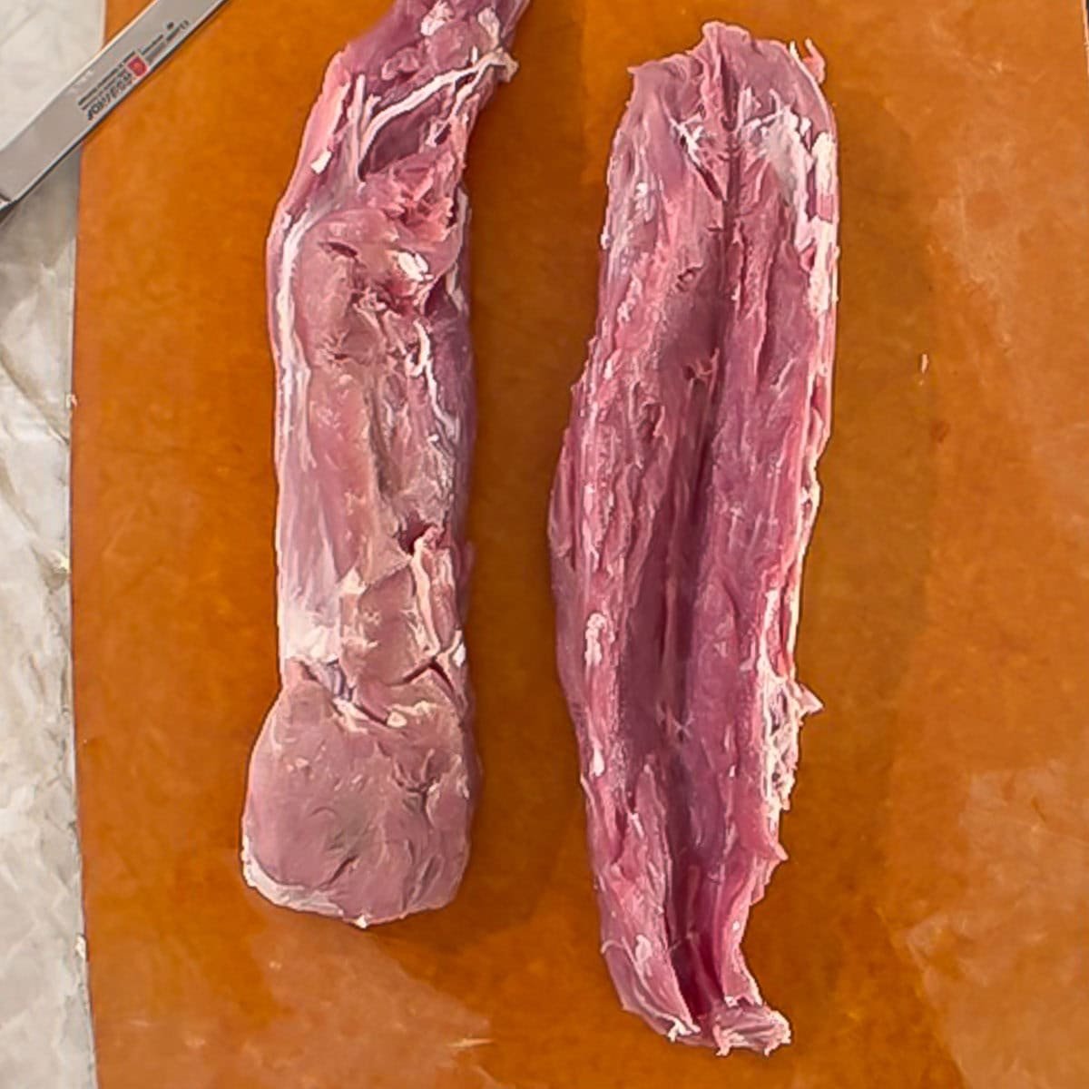 Two pork tenderloins, one on the left is butterflied.