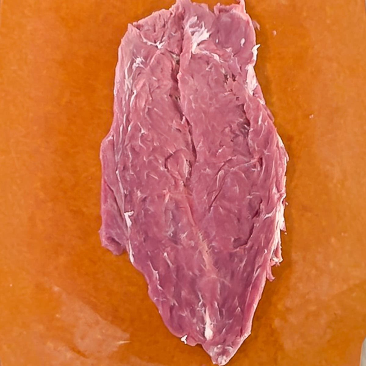 Raw pork tenderloin, pounded to an even thickness.