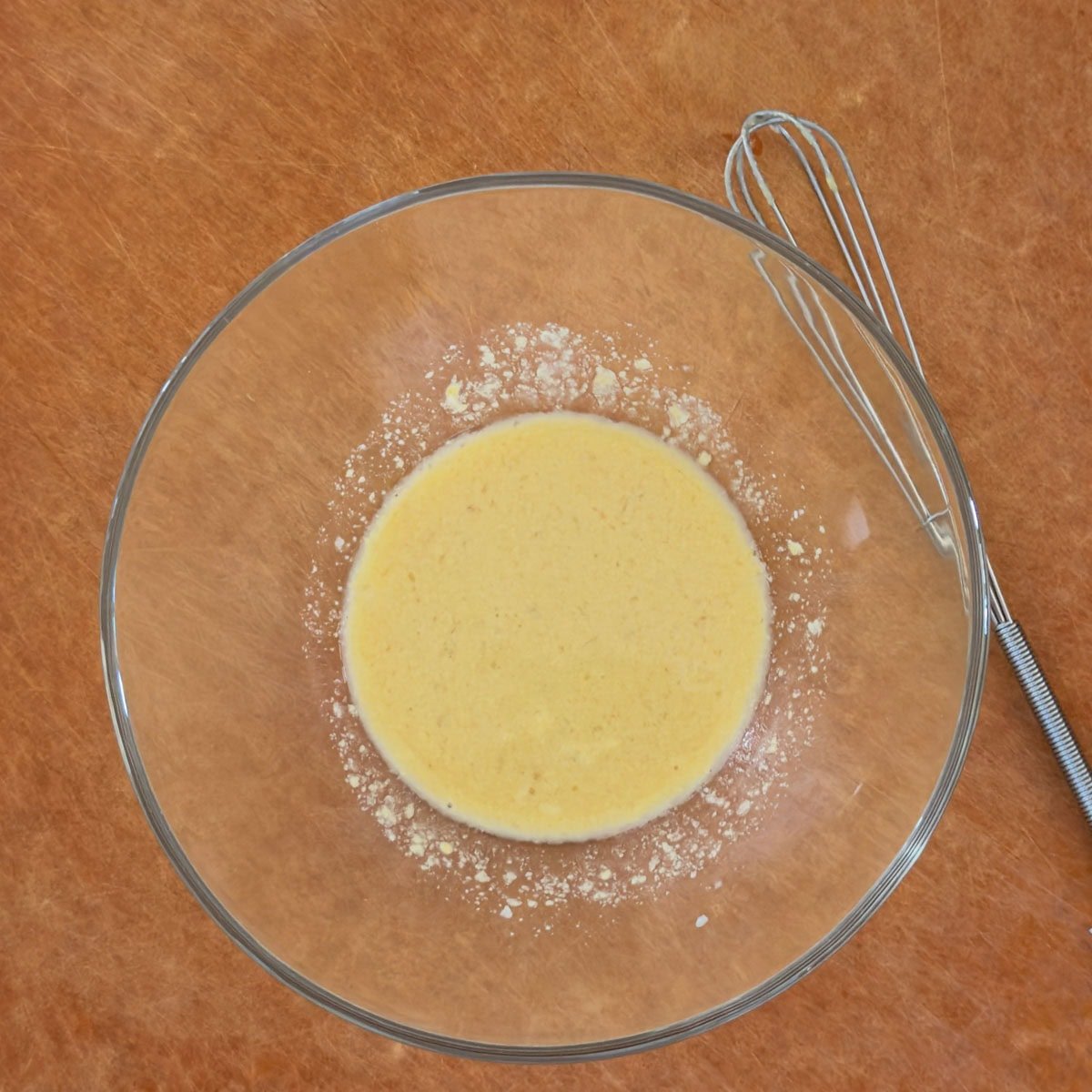 Small bowl holding garlic dijon basting sauce with a whisk alongside.
