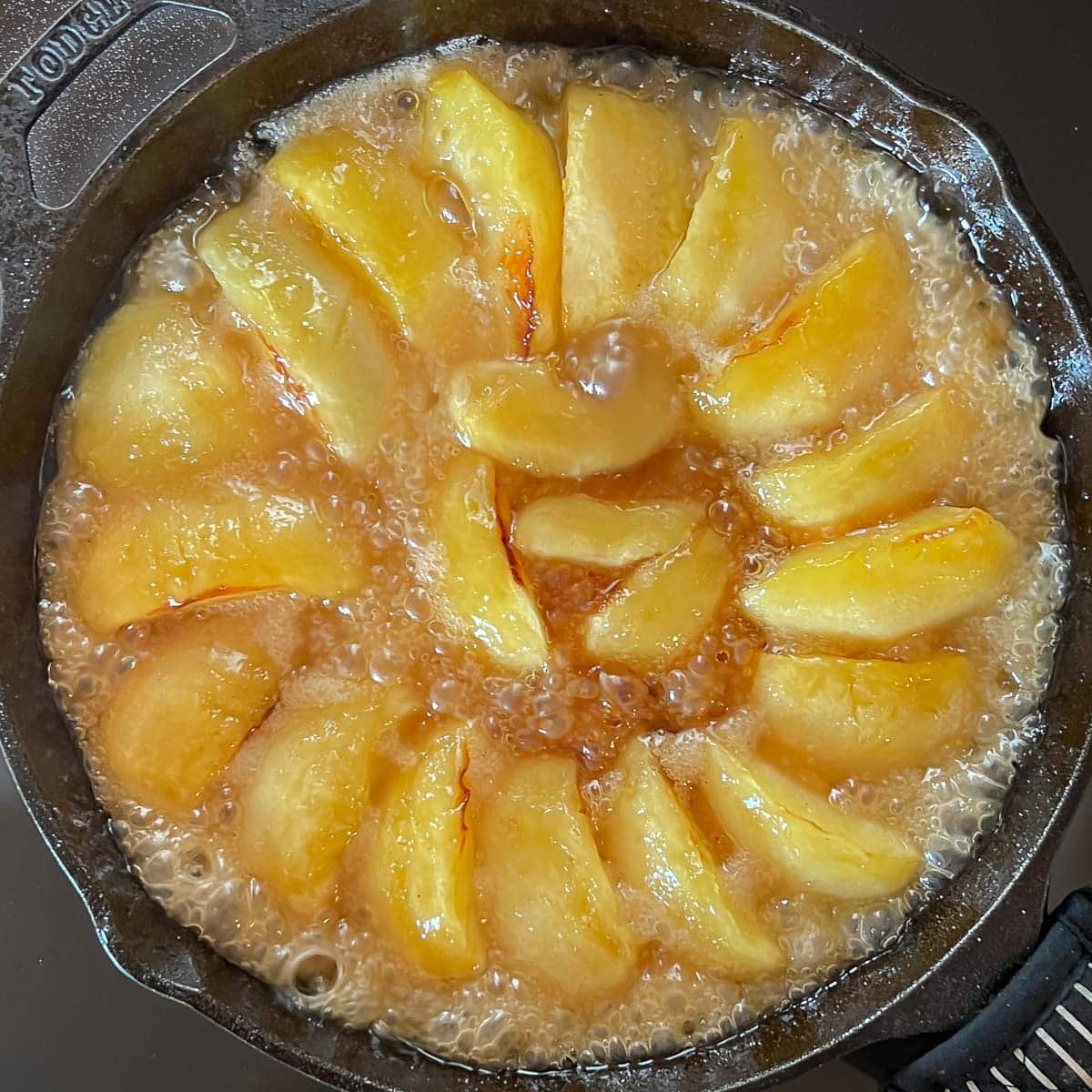 Phase 2 of cooking apples and caramel mixture on stovetop, showing when caramel is darker amber color