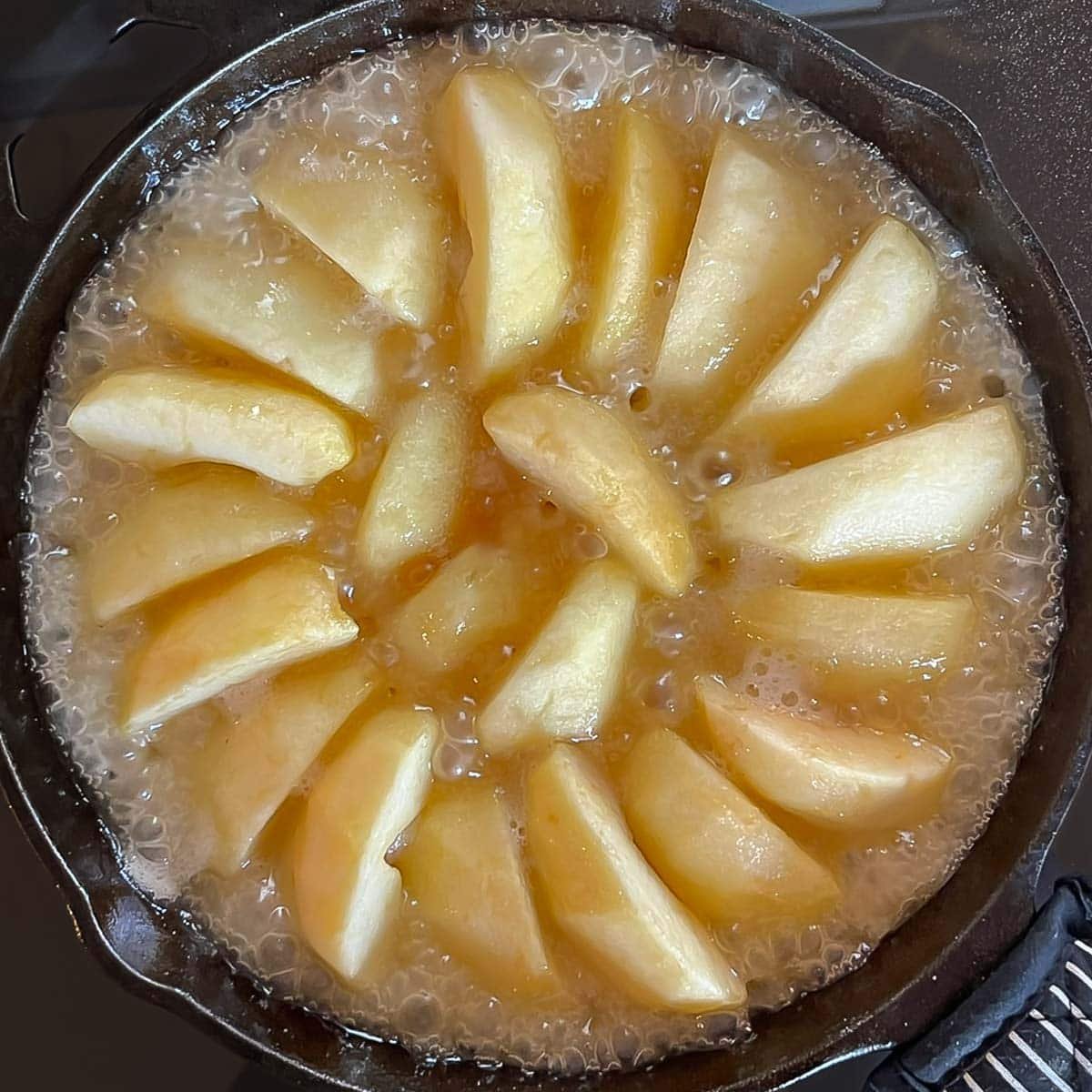 Step 1 of cooking apples and butter-sugar mixture on stovetop, showing when caramel mixture looks like butterscotch