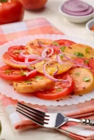 Sliced tomato peach salad on a white plate
