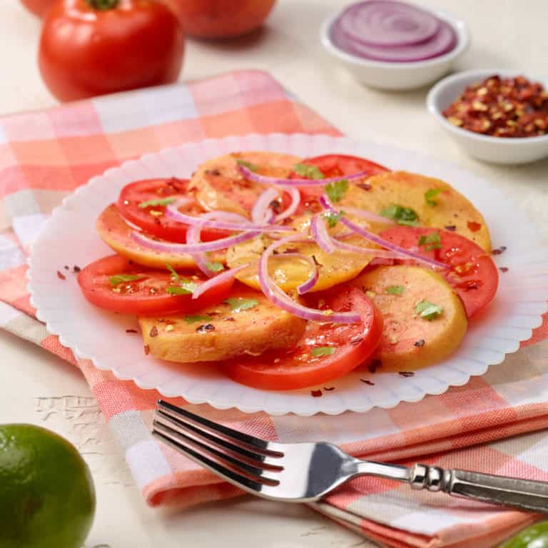 Sliced tomato peach salad on a white plate