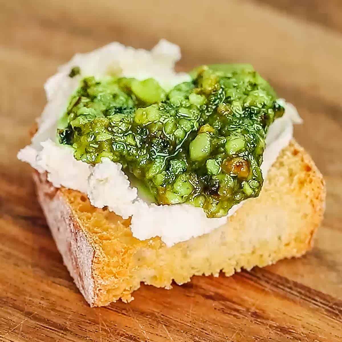 process shot showing putting pesto on goat cheese crostini