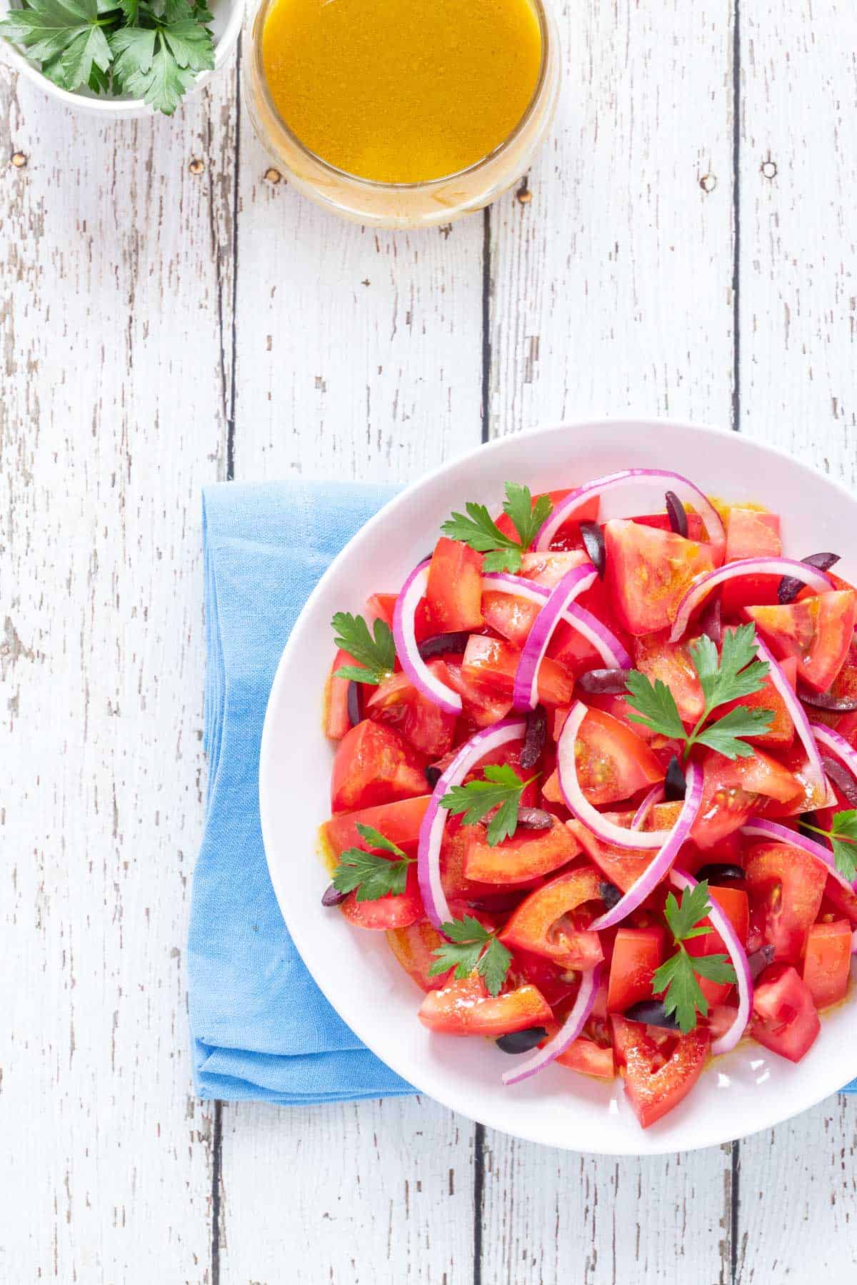 round plate holding Tomato Salad, with Cumin Dressing and fresh parsley on the side.