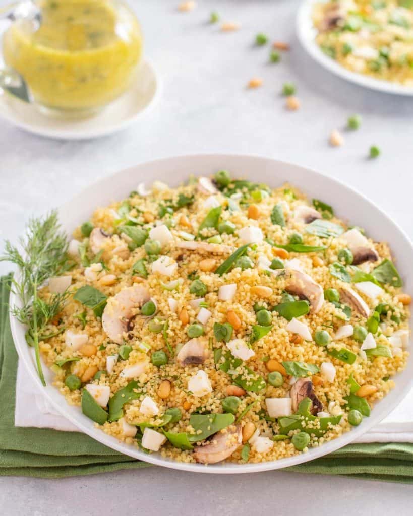 white bowl showing Vegetable Couscous salad, with Dill Vinaigrette on the side.