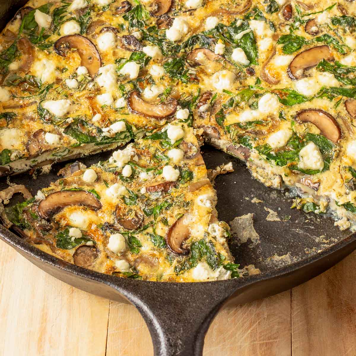 Close up of Vegetable Frittata in cast iron skillet with a piece cut out